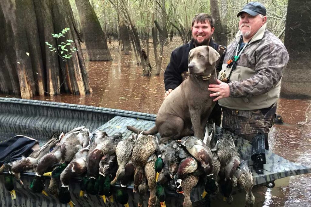 hunters and their dog in a boat with ducks